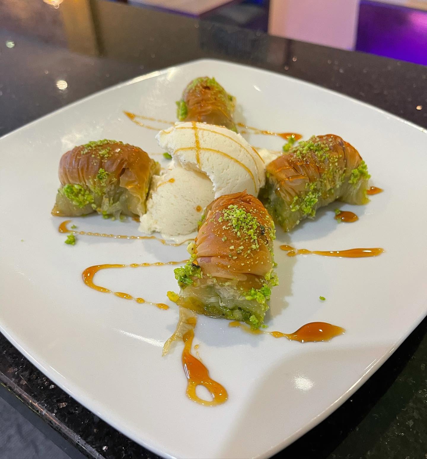 Ela restaurant's crispy pistachio baklava rolls served with a scoop of vanilla ice cream.